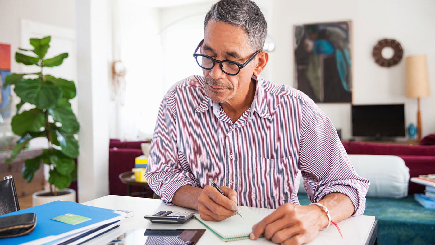 Mature man wearing eyeglasses working on personal finances at home