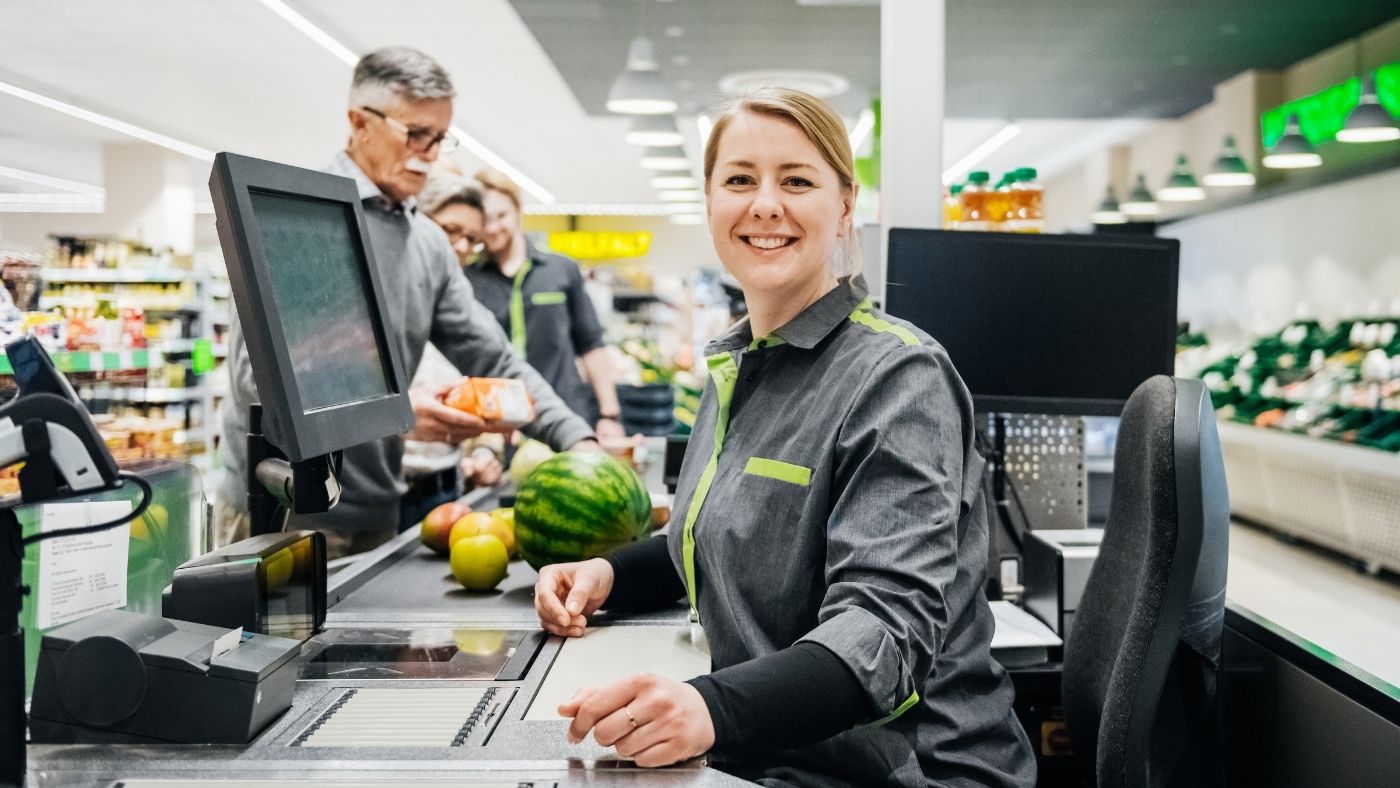 Young female supermarket cashier scanning groceries