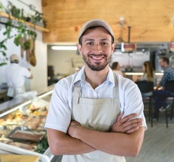 Smiling man wearing an apron in a butcher shop