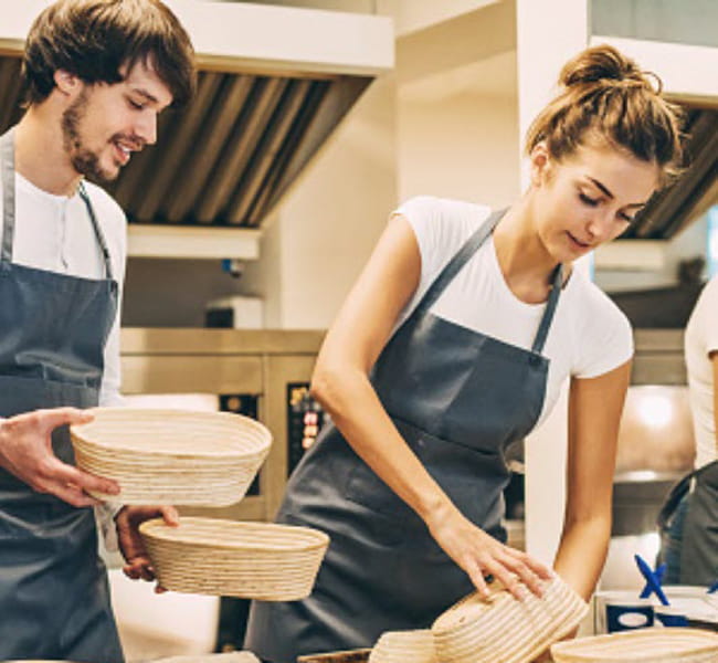 Two bakers work in a kitchen together.