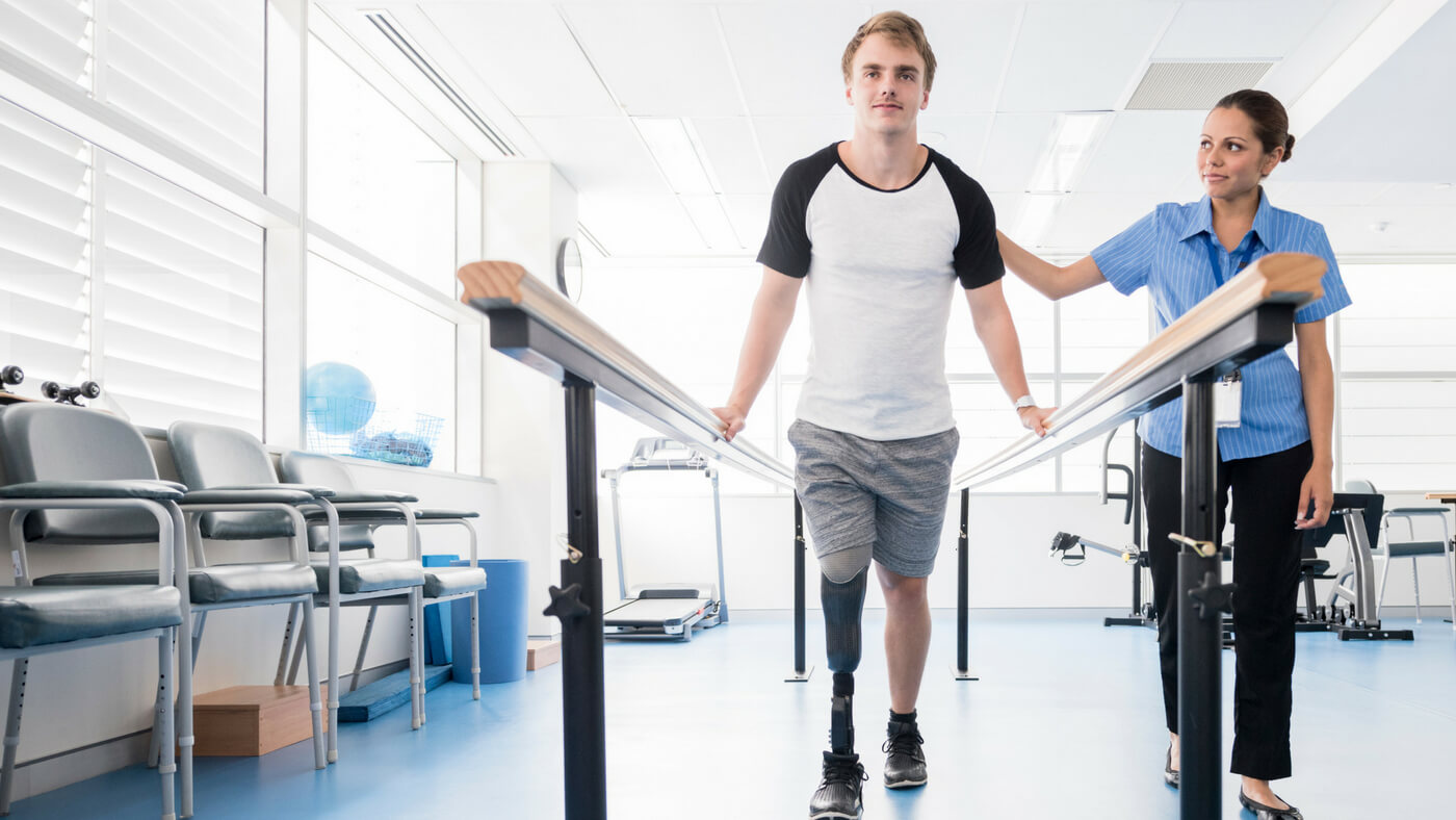 Man with prosthetic leg exercising with a nurse attending