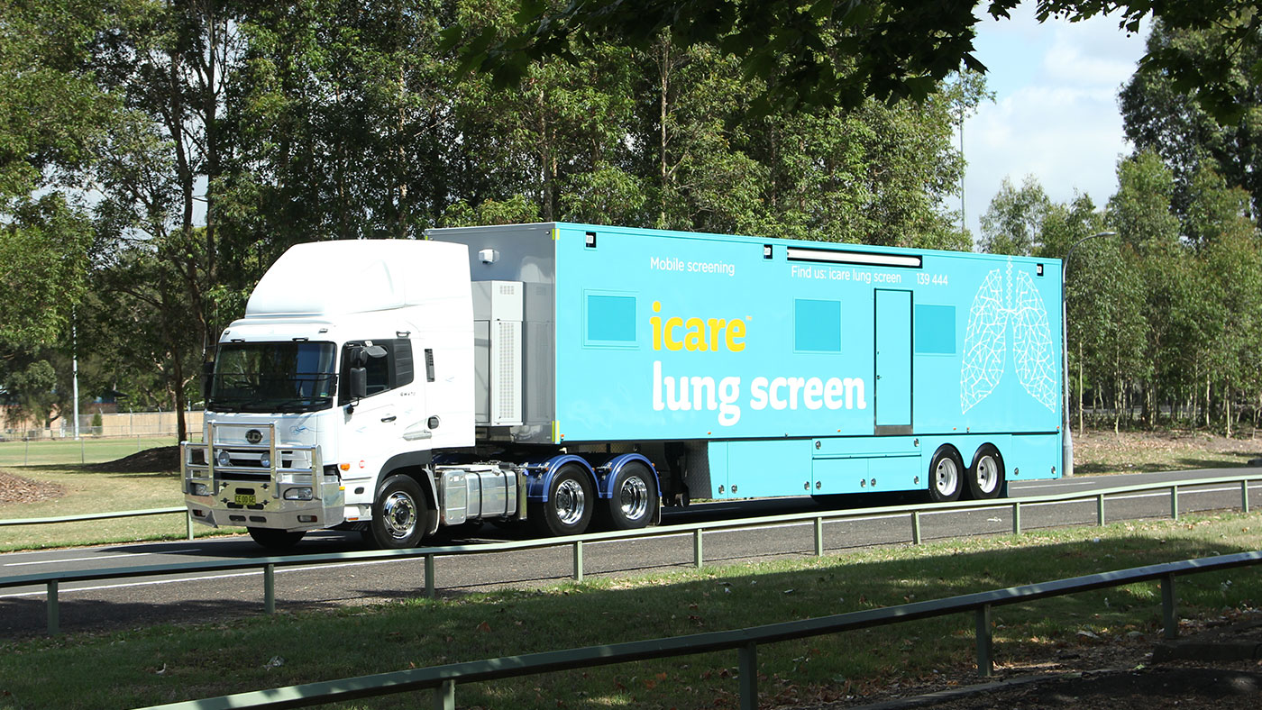icare lung screening bus driving through a leafy suburb.