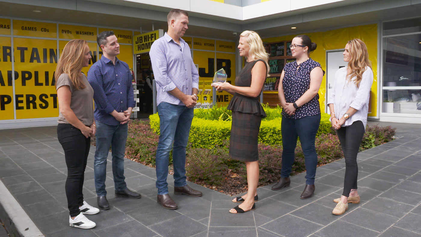 icare team presenting jb-hi delegates with icare-aware award outside jb hi-fi store.