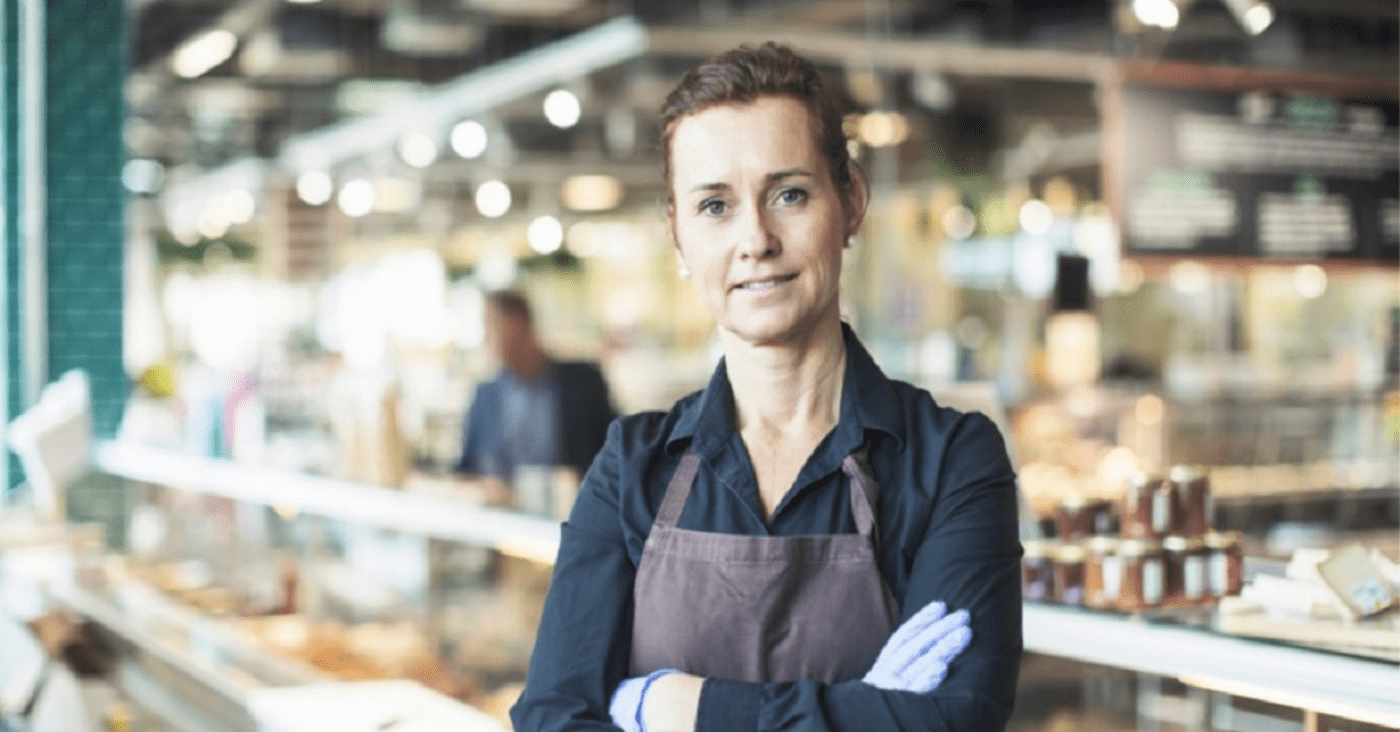 Confident retail worker stands with arms crossed and smiles.