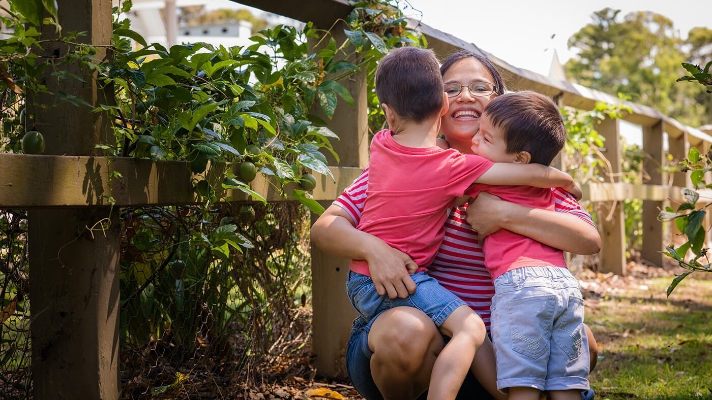 Woman cuddling two young children