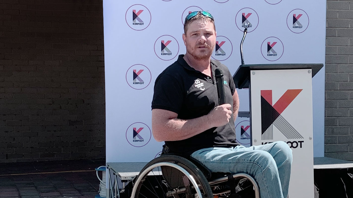 Ben Houlison paralympian speaker with a microphone speaking to the employees at Kerfoot