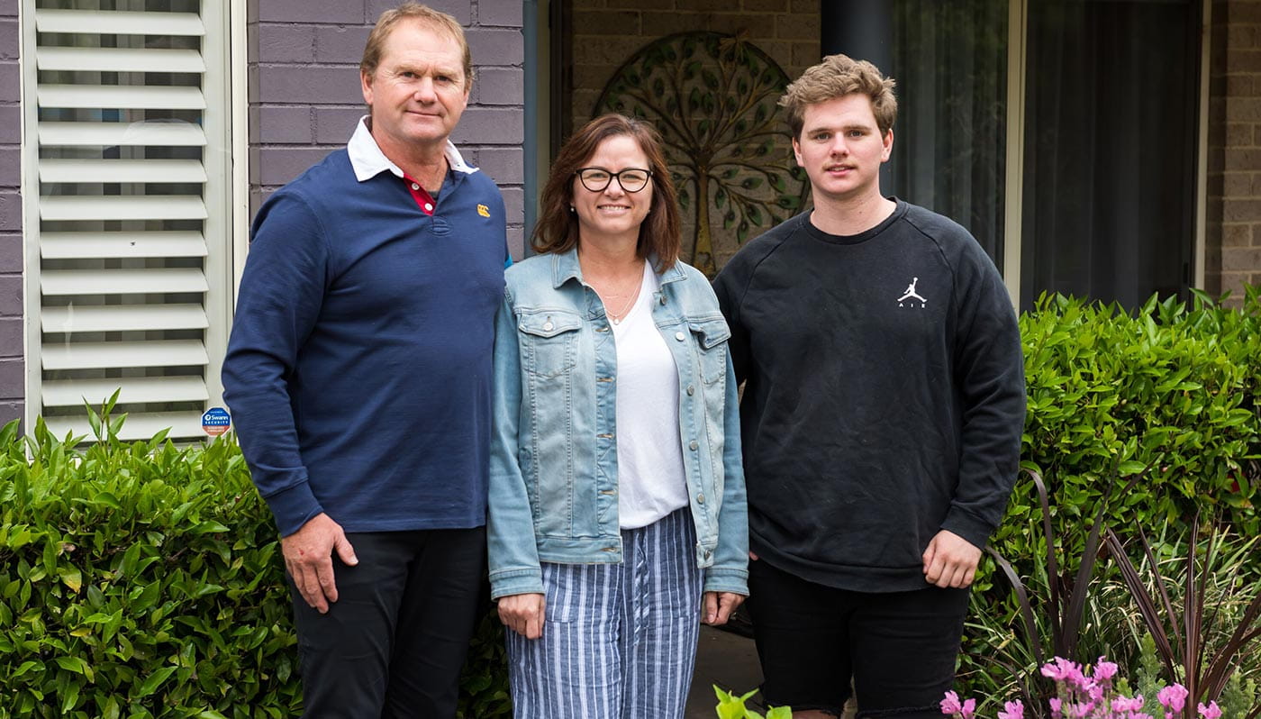 Adam Kleining and his parents in front of house
