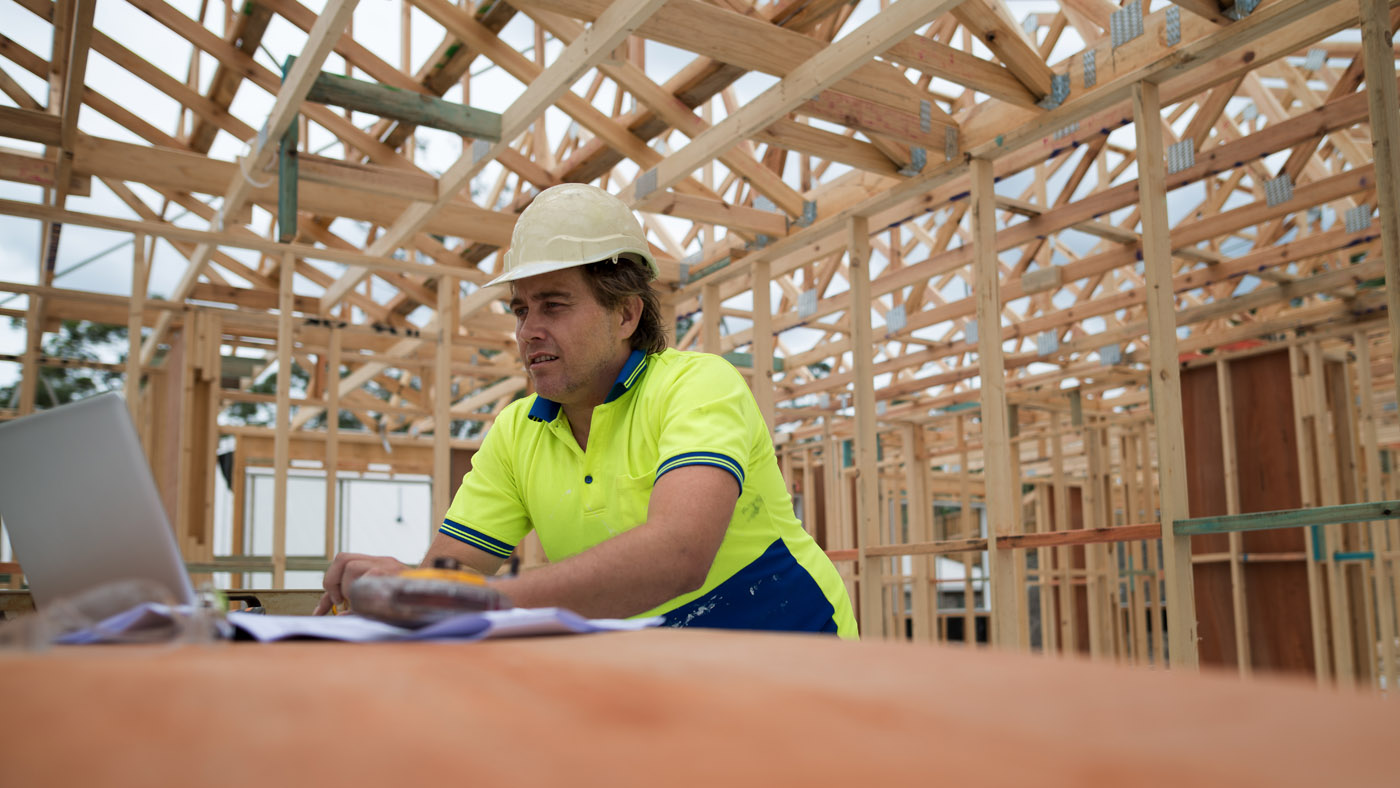 Builder looking at laptop on construction site.