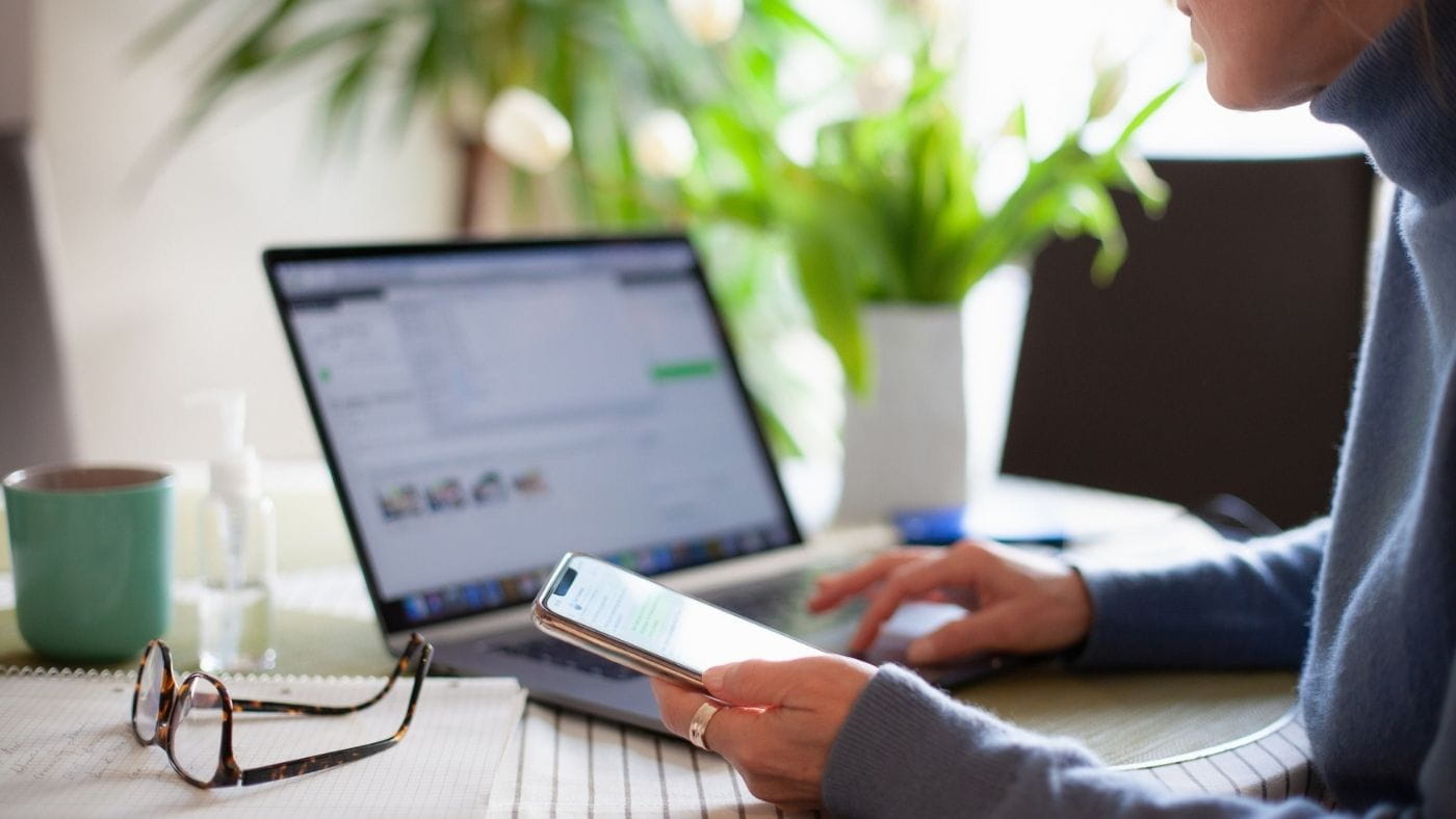 Woman working from home and multitasking with her mobile phone and laptop