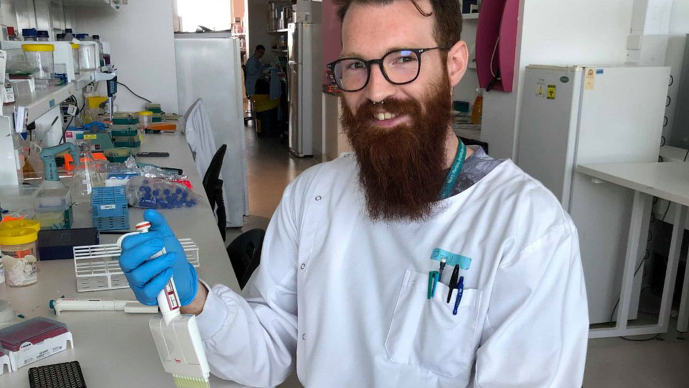 research scholarship recipient Joel in a lab smiling at the camera