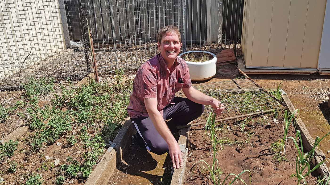A man sitting in a vegetable garden.
