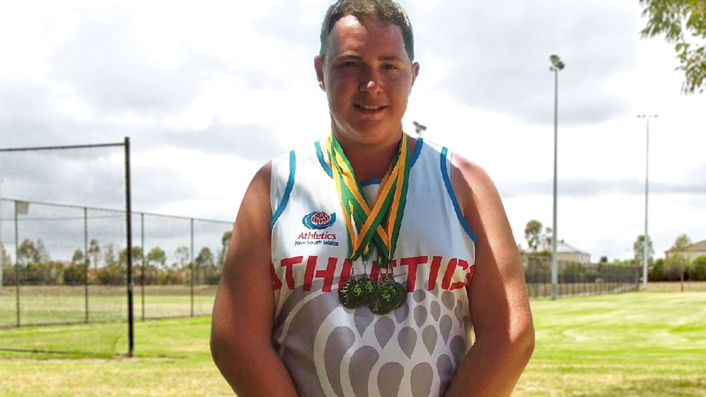 A man with medals around his neck is in a sports ground.
