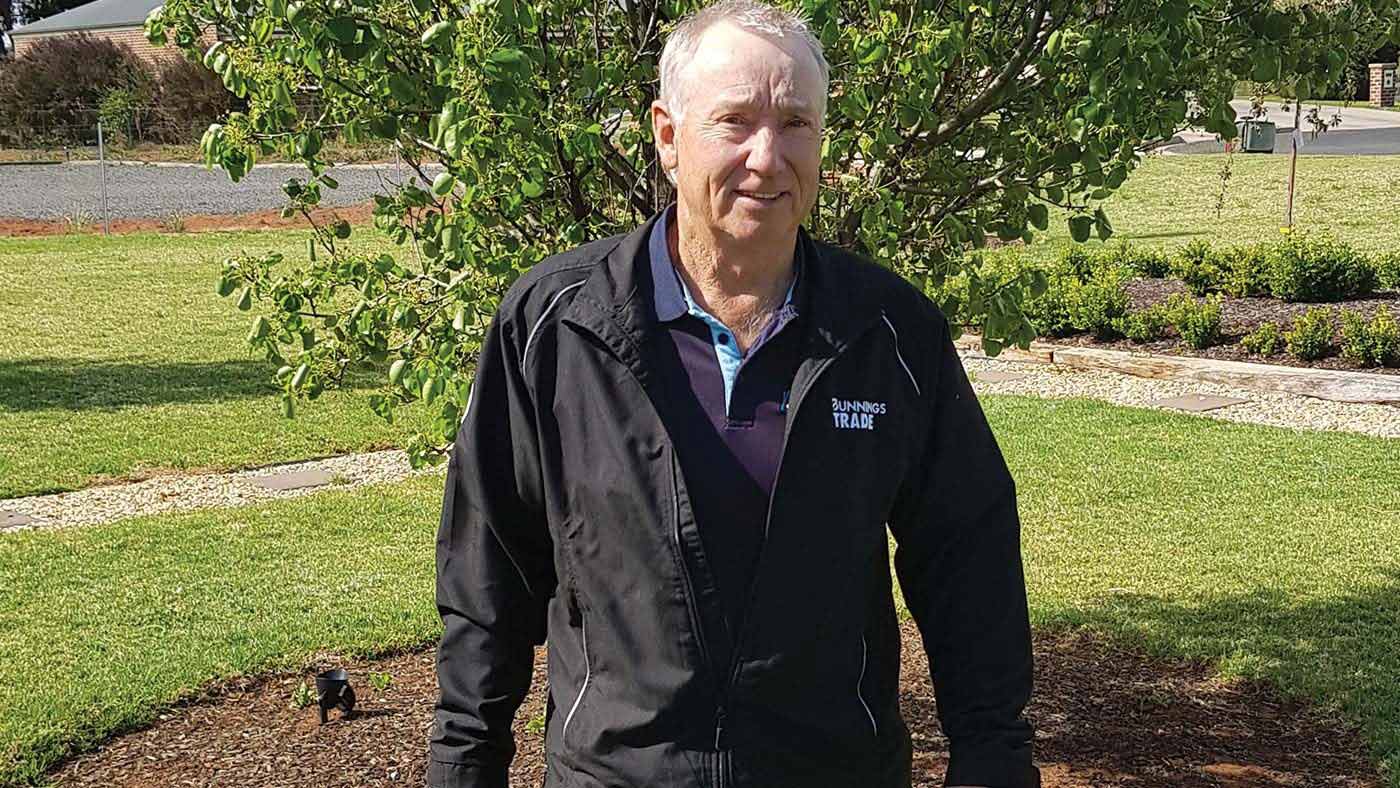 A man is standing in a garden looking at the camera.