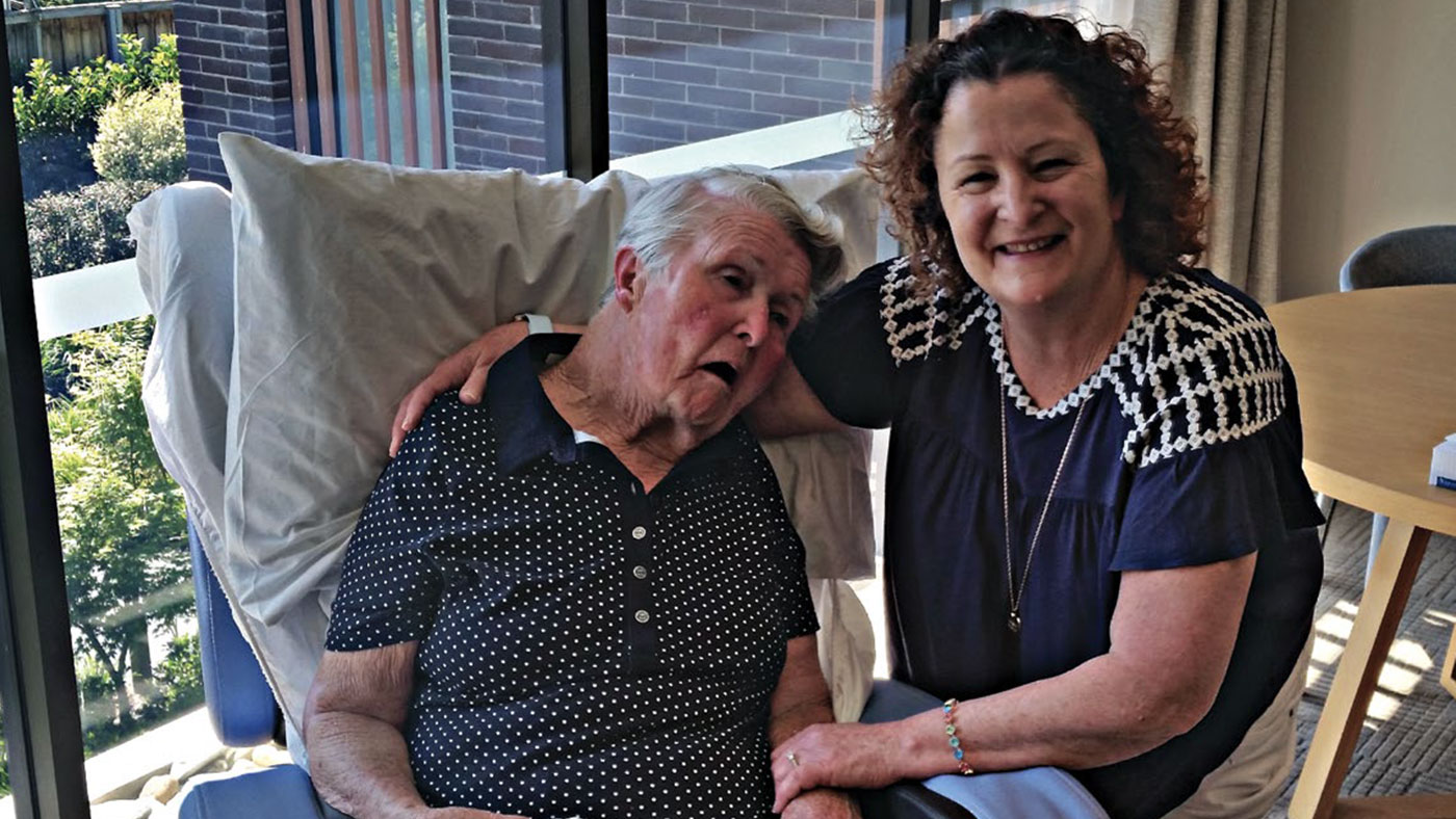 Cathy Brown with her mother, June Lewis. June is a Lifetime Care participant. They are both sitting down in a lounge room.