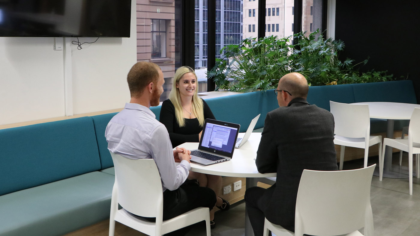 Industry Champion Neven sits at a table talking with two colleagues.