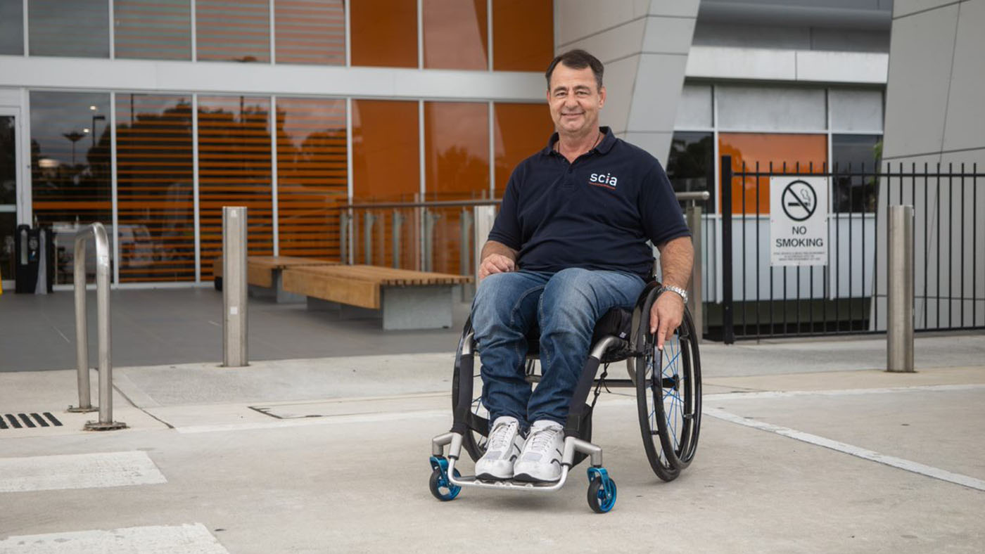 Jason Wright sitting in his wheelchair outside of a hospital