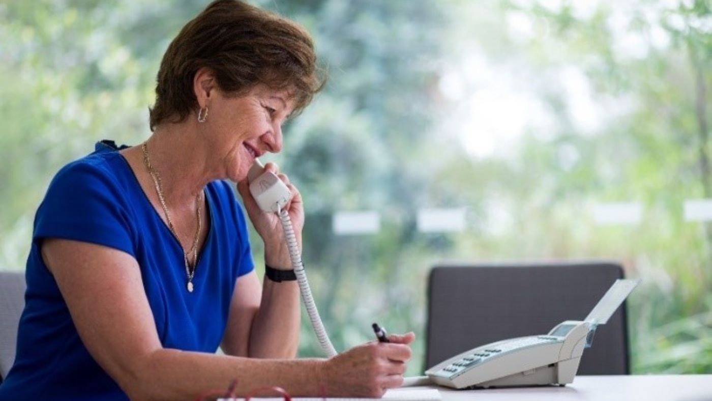 News Story Jocelyn Jocelyn, founder of EPP siting at her desk talking on a white telephone.