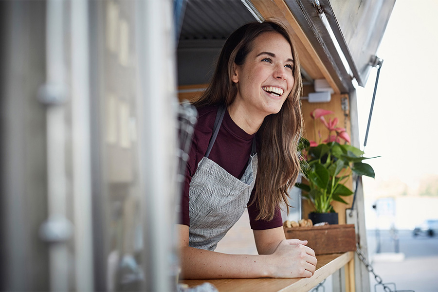A girl smiling wearing an apron in a food truck