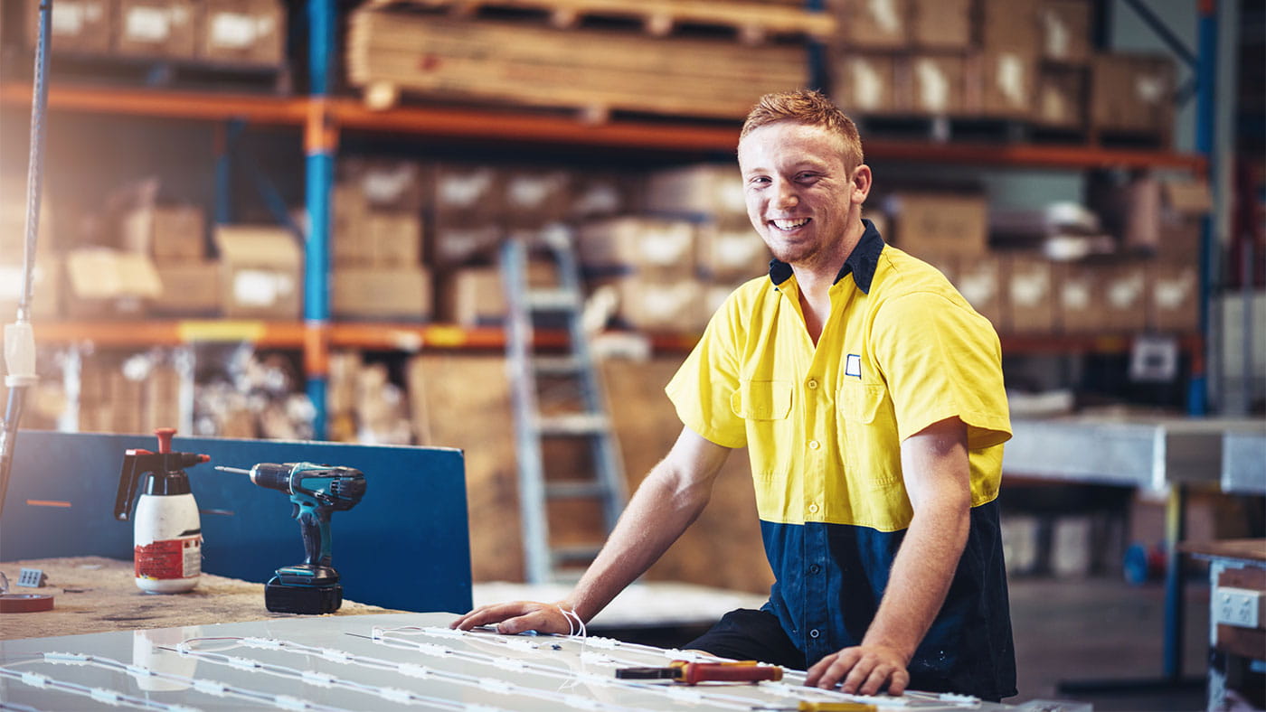 A man smiling at the camera in hi-vis in a factory