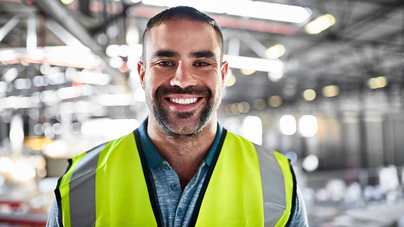 smiling man in hi-vis in a construction site.