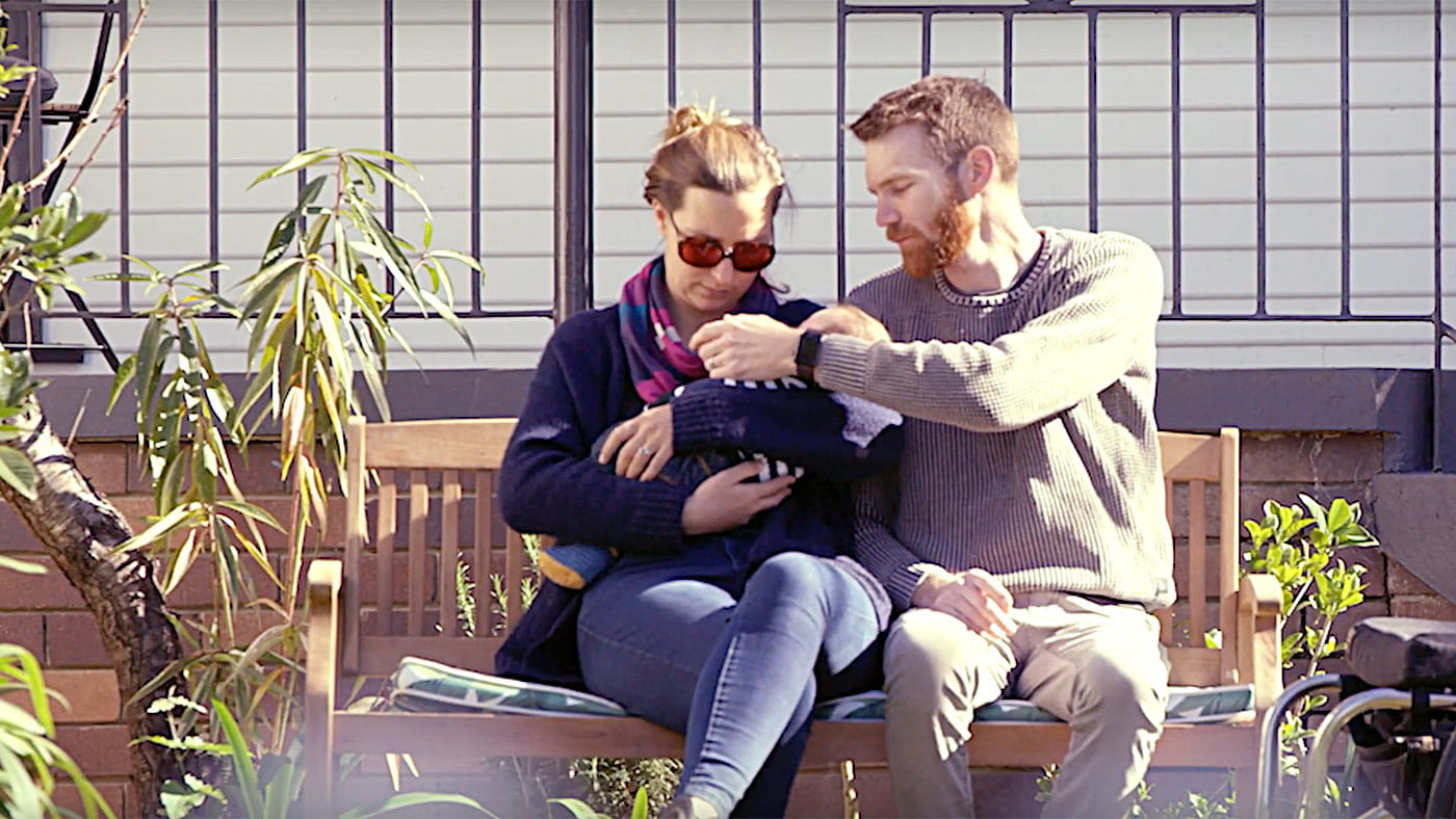 man and woman holding a child in the garden