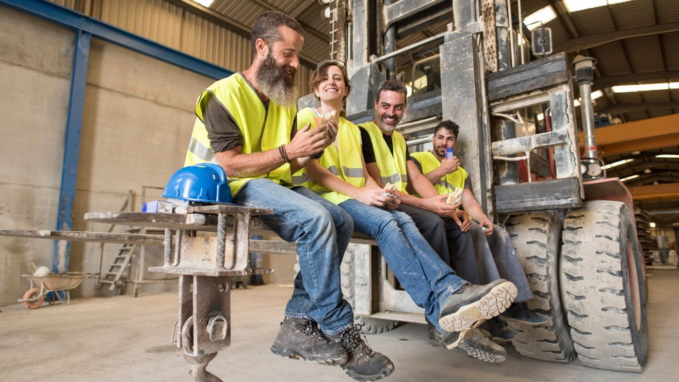 Four factory workers in high visibility vests taking a break 